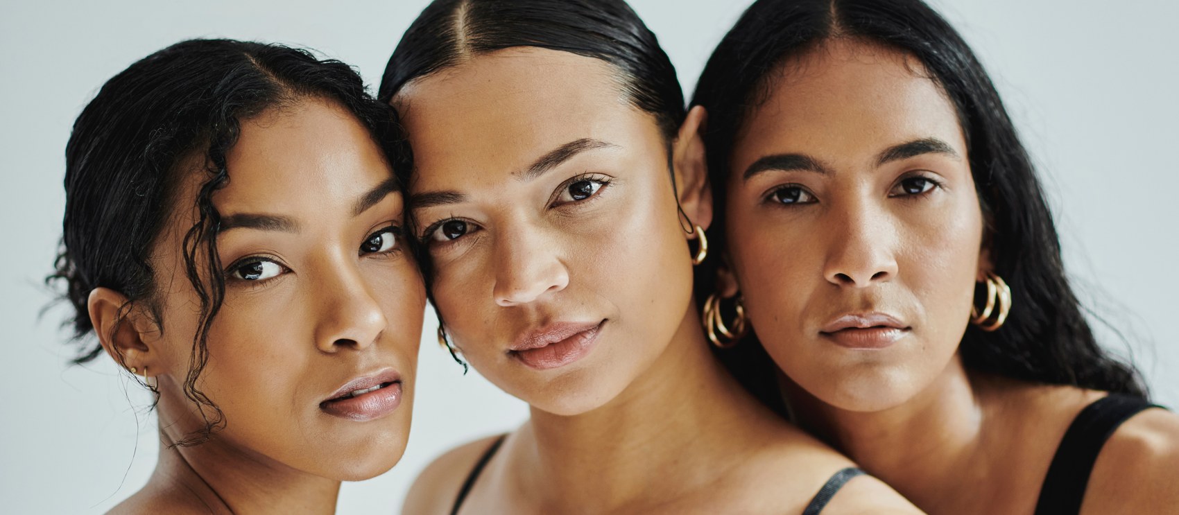 Three women with melasma-prone skin, bare-faced in calm studio light