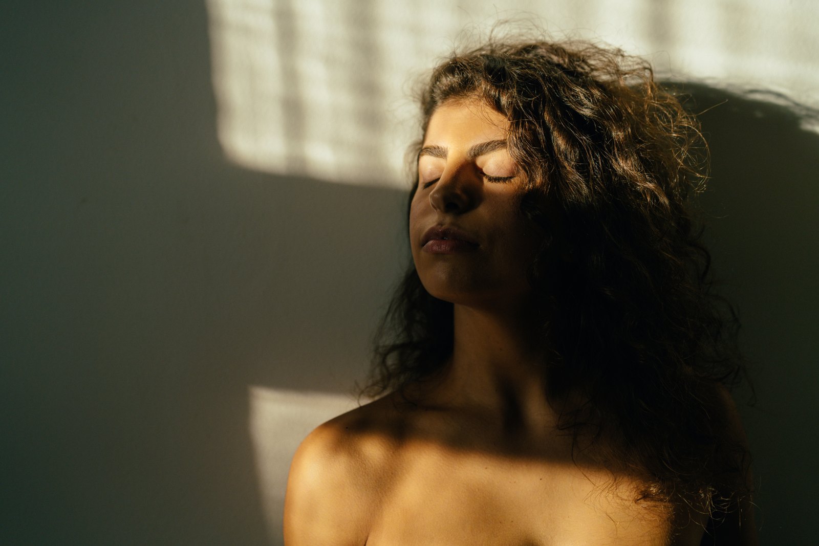Woman with melasma-prone skin in soft dappled window light